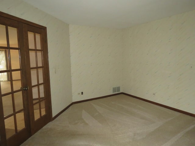 unfurnished room with carpet floors, french doors, visible vents, and baseboards