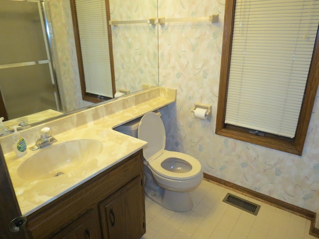 bathroom featuring visible vents, toilet, vanity, baseboards, and wallpapered walls