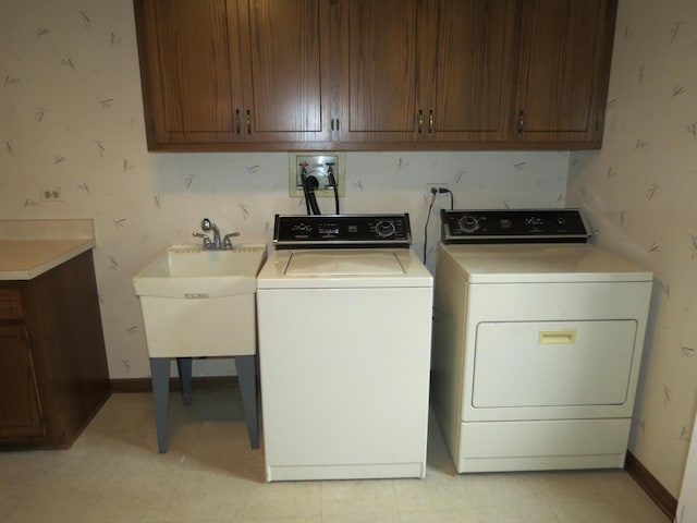 clothes washing area featuring baseboards, cabinet space, independent washer and dryer, and a sink