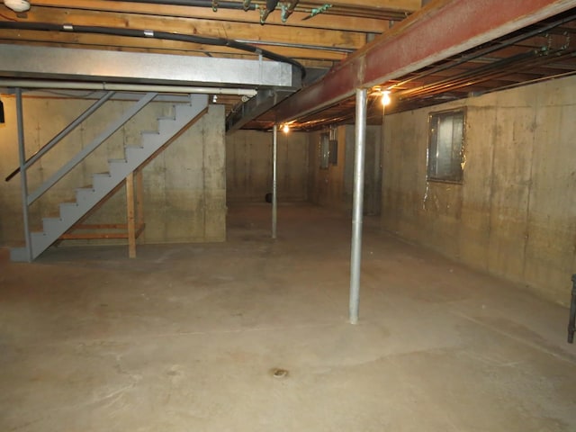 unfinished below grade area with electric panel and stairway