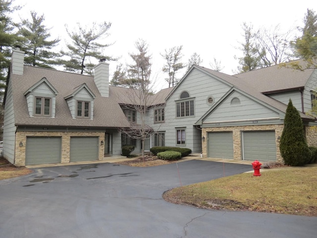 view of front of home featuring driveway, a shingled roof, and a chimney