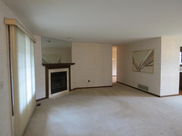 unfurnished living room featuring light colored carpet, baseboards, visible vents, and a tiled fireplace