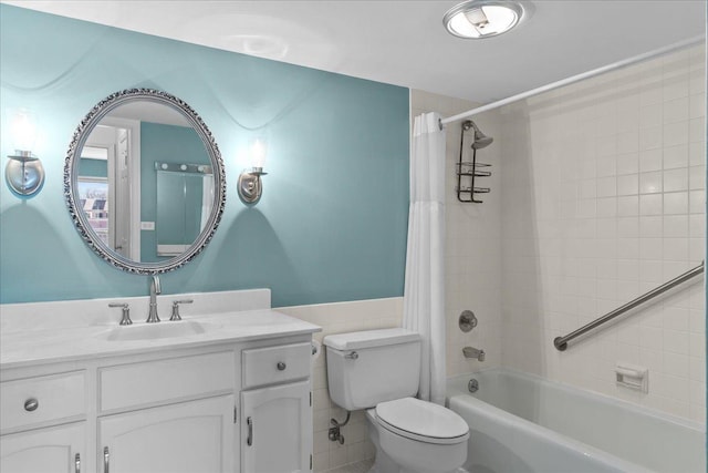 bathroom with toilet, a wainscoted wall, vanity, tile walls, and shower / bath combo