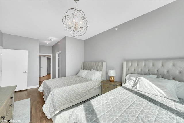 bedroom with dark wood-style floors, baseboards, and a chandelier