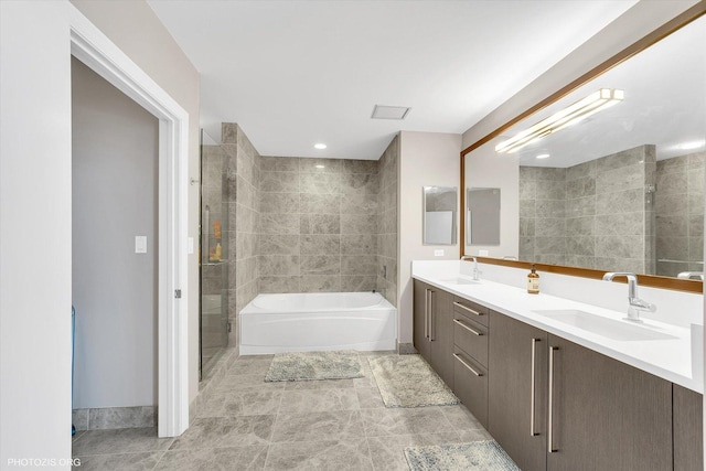 bathroom featuring a garden tub, double vanity, a stall shower, and a sink