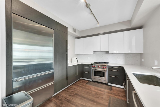 kitchen featuring visible vents, dark wood-type flooring, white cabinetry, high end appliances, and a sink