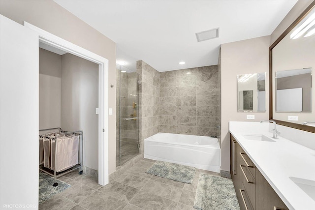 bathroom with visible vents, a garden tub, a stall shower, a sink, and double vanity