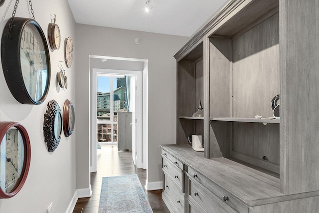 corridor featuring dark wood-type flooring and baseboards