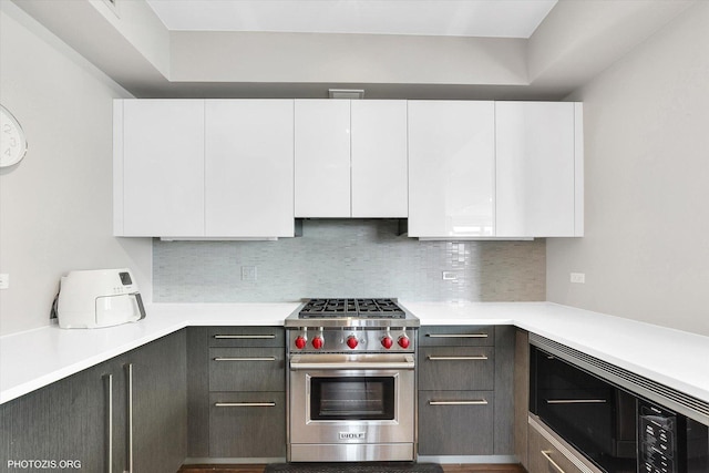 kitchen featuring light countertops, decorative backsplash, stainless steel appliances, white cabinetry, and modern cabinets