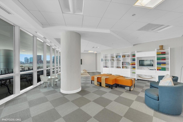 living area with a drop ceiling, visible vents, a city view, and ornate columns