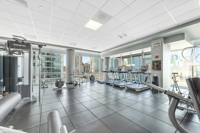 exercise room with floor to ceiling windows, a view of city, and a paneled ceiling