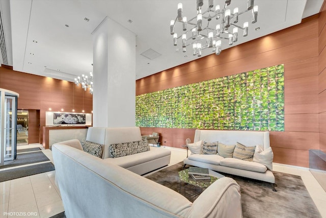 living area featuring tile patterned flooring, wooden walls, and an inviting chandelier