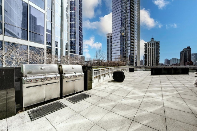 view of patio / terrace featuring a city view, an outdoor kitchen, and a grill