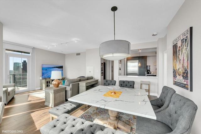 dining area with visible vents, rail lighting, baseboards, and wood finished floors