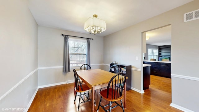 dining room with light wood finished floors, plenty of natural light, visible vents, and baseboards