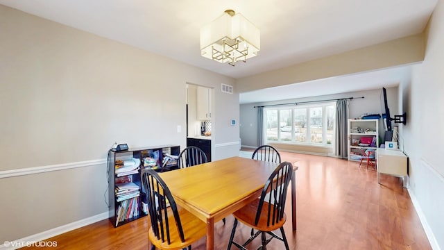 dining room with light wood-style floors, visible vents, and baseboards