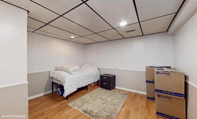 bedroom featuring baseboards, visible vents, a drop ceiling, and wood finished floors