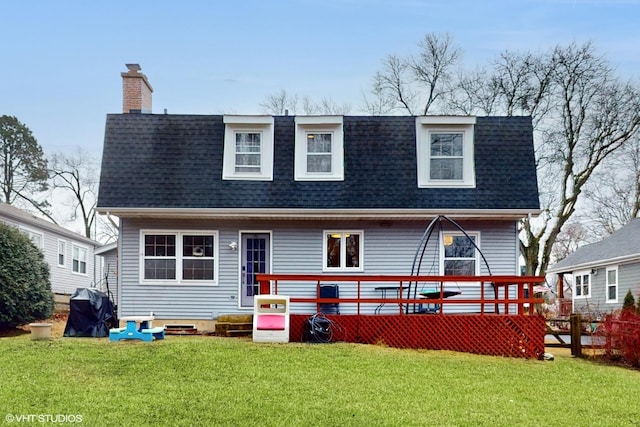 back of property with a yard, a shingled roof, a chimney, and a wooden deck