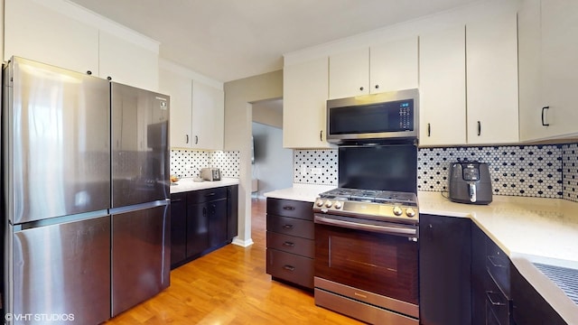 kitchen featuring light wood finished floors, white cabinetry, stainless steel appliances, and light countertops