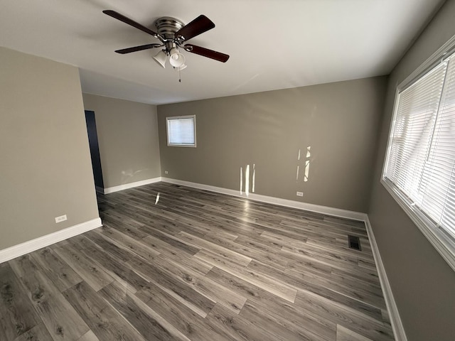 unfurnished room featuring a ceiling fan, visible vents, baseboards, and dark wood-type flooring