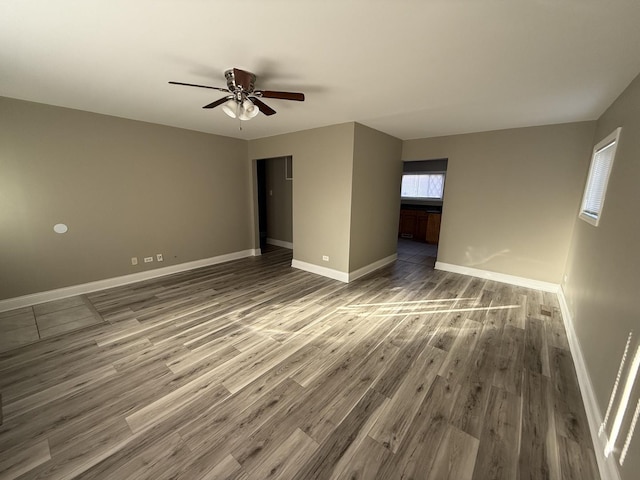 spare room featuring ceiling fan, baseboards, and wood finished floors