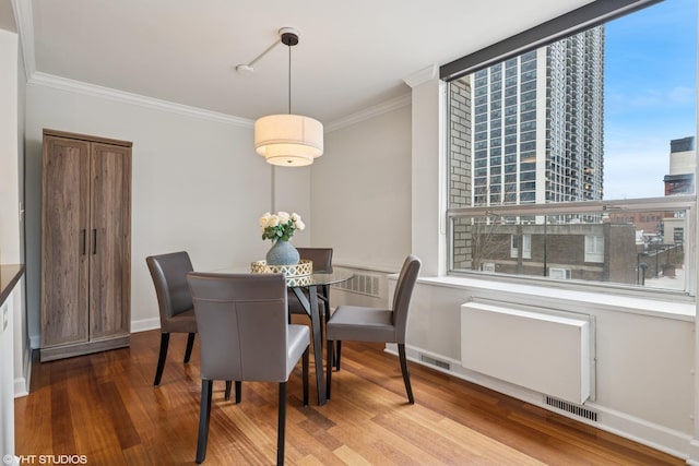 dining area with visible vents, crown molding, baseboards, and wood finished floors