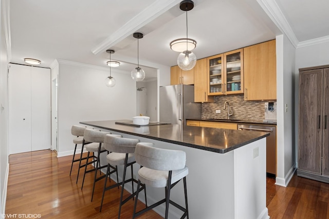 kitchen with crown molding, dark countertops, appliances with stainless steel finishes, a sink, and a kitchen bar