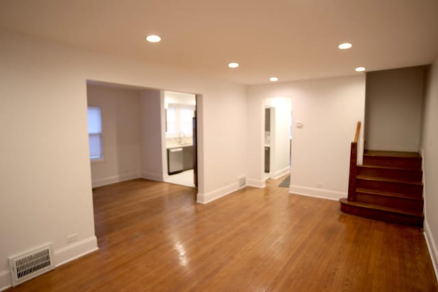 empty room featuring stairs, visible vents, wood finished floors, and recessed lighting