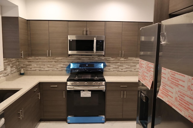 kitchen with modern cabinets, appliances with stainless steel finishes, backsplash, and dark brown cabinets