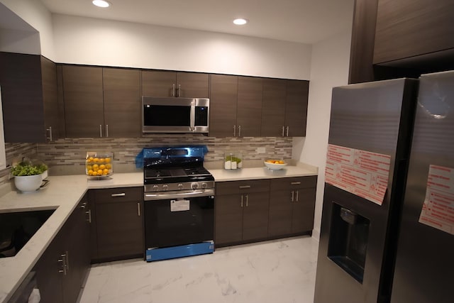 kitchen featuring dark brown cabinetry, marble finish floor, appliances with stainless steel finishes, and decorative backsplash