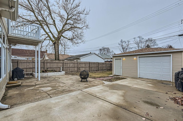 view of patio / terrace featuring driveway, fence, a fire pit, and an outdoor structure