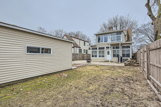 rear view of house featuring entry steps, a lawn, a fenced backyard, a chimney, and a patio area