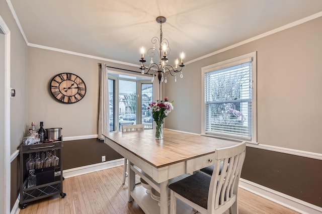 dining area with baseboards, an inviting chandelier, hardwood / wood-style flooring, and crown molding