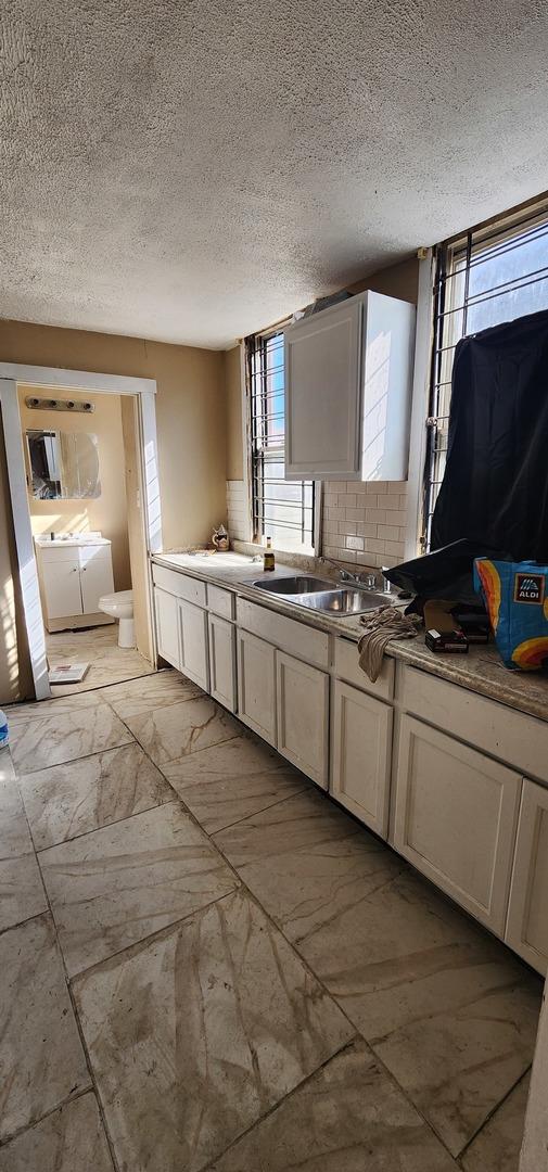 kitchen featuring a sink, marble finish floor, a textured ceiling, separate washer and dryer, and backsplash