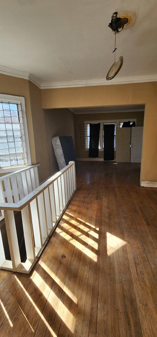 corridor featuring wood-type flooring, ornamental molding, and baseboards