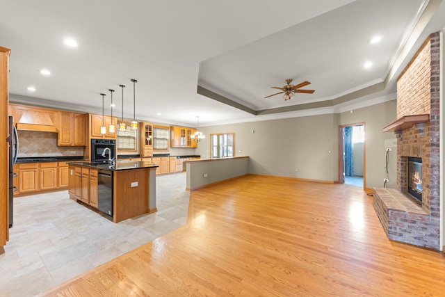 2811 Haven Ct, Naperville, IL 60564 - kitchen with a fireplace, a kitchen island with sink, dark countertops, tasteful backsplash, and light wood-style floors