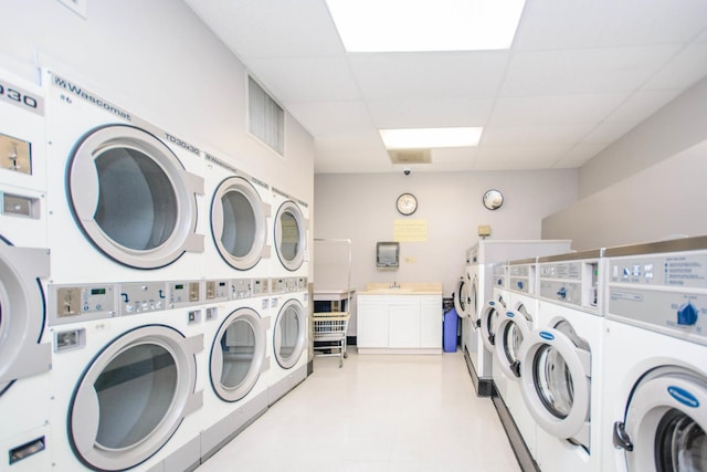 community laundry room with stacked washer / dryer, washing machine and clothes dryer, and visible vents