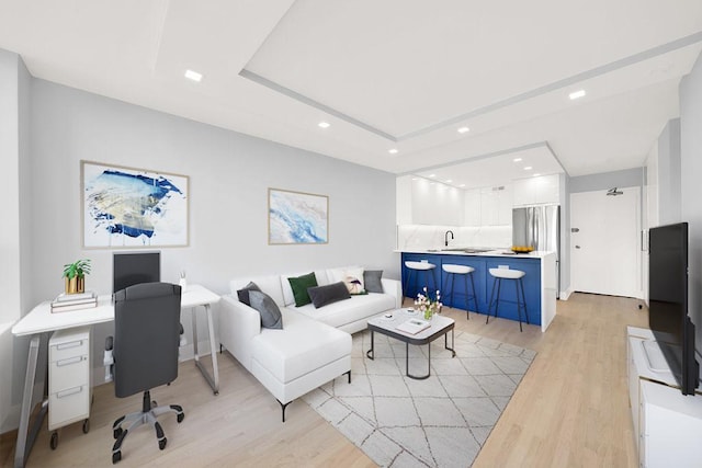 living area with light wood-style floors, a tray ceiling, and recessed lighting