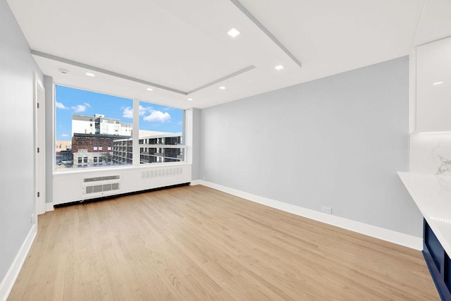 empty room with a view of city, recessed lighting, wood finished floors, and baseboards