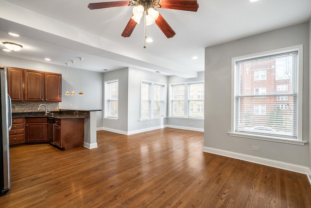 kitchen with a peninsula, baseboards, open floor plan, dark wood-style floors, and dark countertops