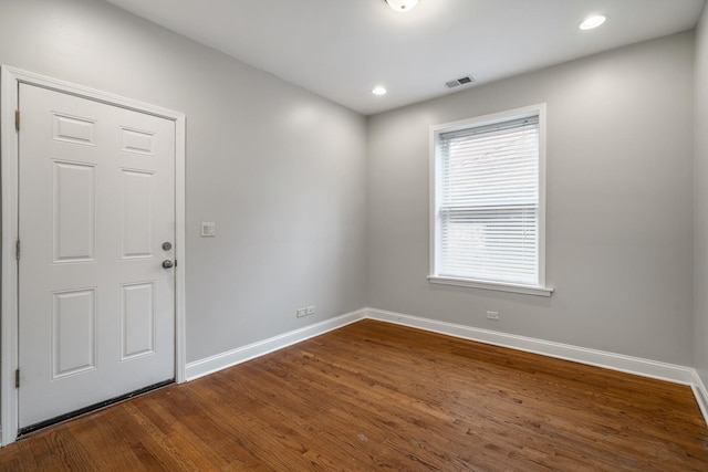 empty room featuring recessed lighting, dark wood-style flooring, visible vents, and baseboards