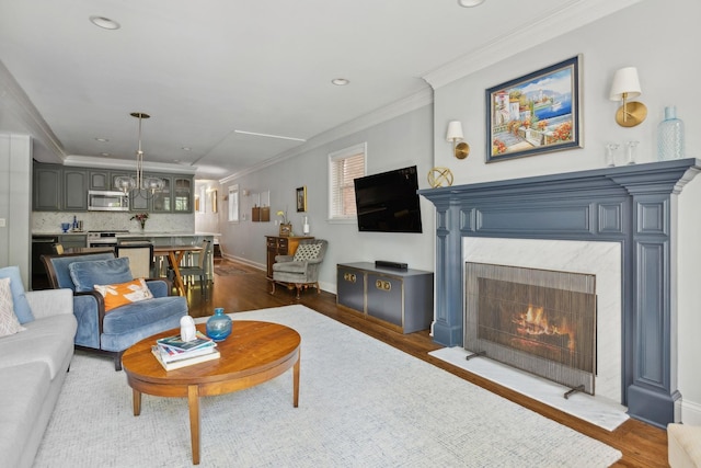 living room featuring ornamental molding, wood finished floors, a high end fireplace, and baseboards