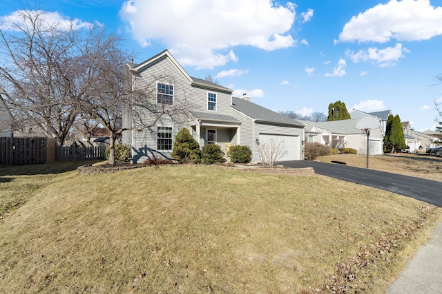 traditional-style home with driveway, a garage, a chimney, fence, and a front yard