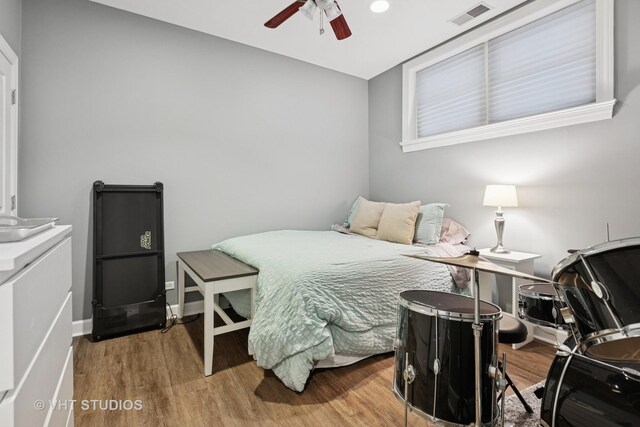 bedroom with ceiling fan, wood finished floors, visible vents, and baseboards