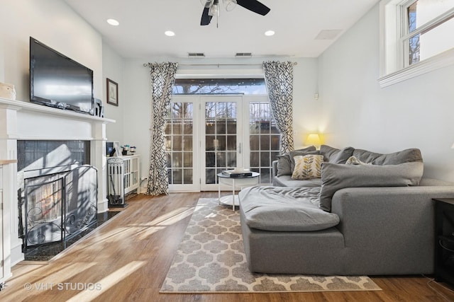 living area with a tiled fireplace, wood finished floors, and visible vents