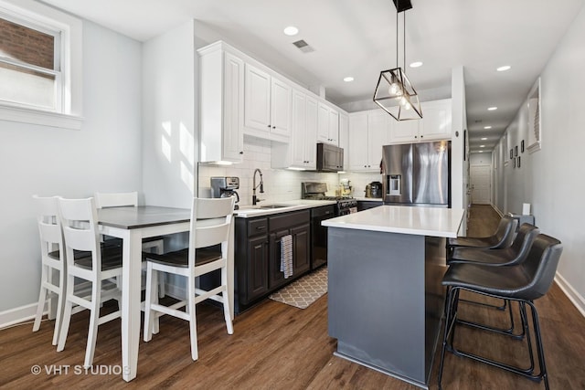 kitchen with dark wood-type flooring, a sink, backsplash, white cabinetry, and stainless steel appliances