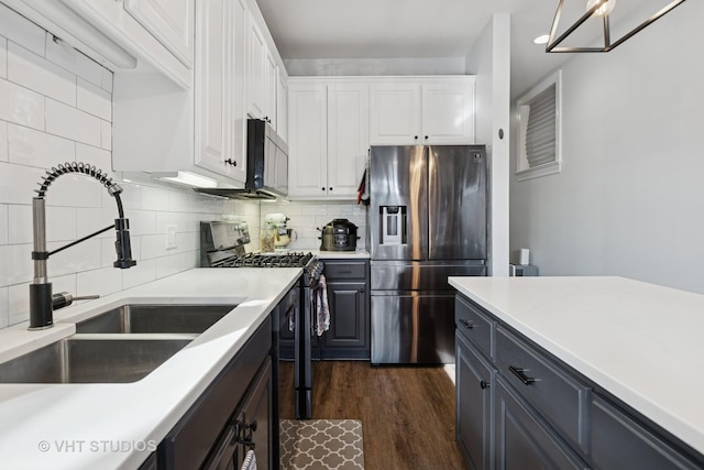 kitchen featuring a sink, tasteful backsplash, dark wood-style floors, stainless steel appliances, and white cabinets