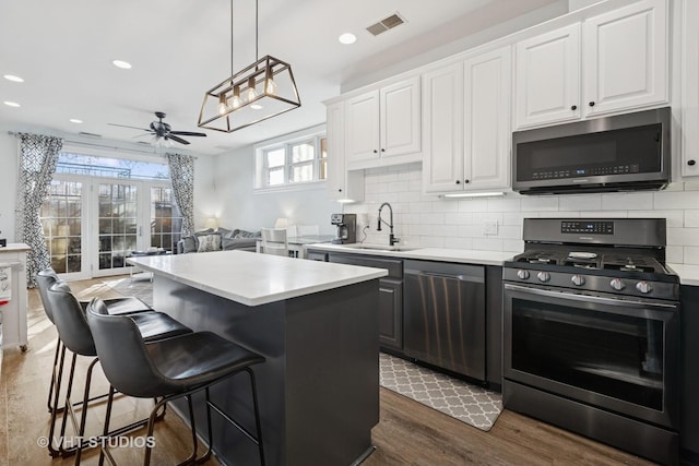 kitchen featuring tasteful backsplash, appliances with stainless steel finishes, a center island, and a sink