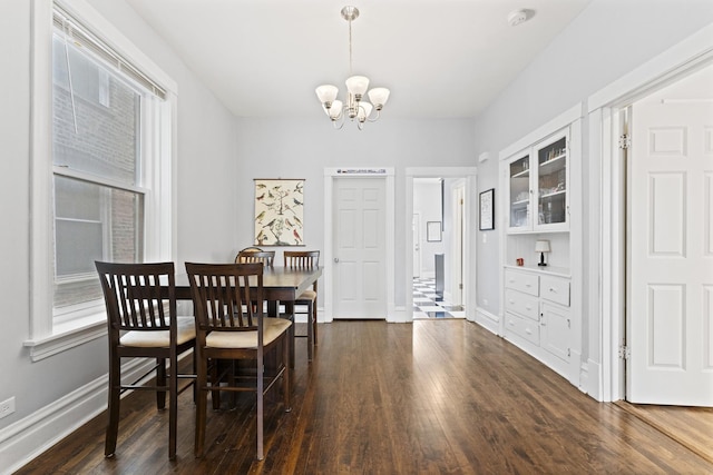 dining space featuring a chandelier, hardwood / wood-style flooring, and baseboards