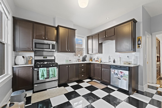 kitchen with stainless steel appliances, light floors, light countertops, and dark brown cabinetry